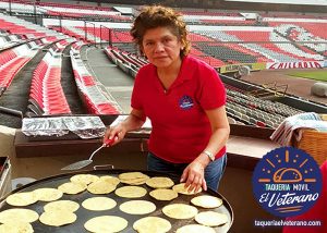 Mujer cocinando tortillas en estadio.